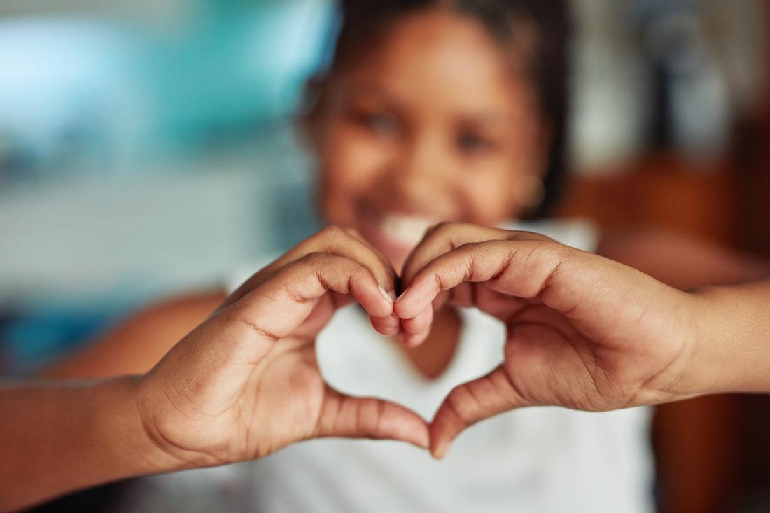 Young child forming a heart shape with their hands