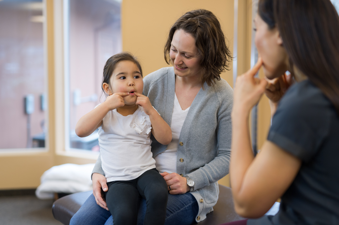 Provider and child making funny faces at doctors office