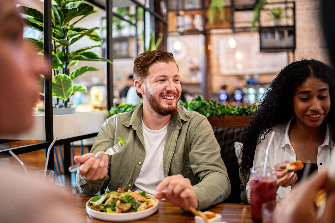 Happy man eating salad with friends.jpg