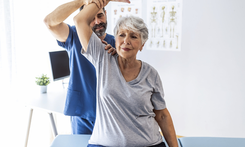 Clinician stretching womans arm overhead